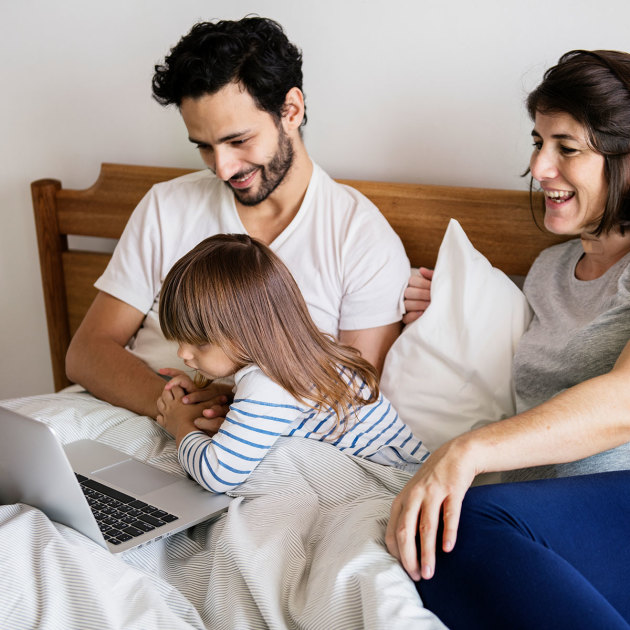 Family_in_bed_looking_over_their_laptop